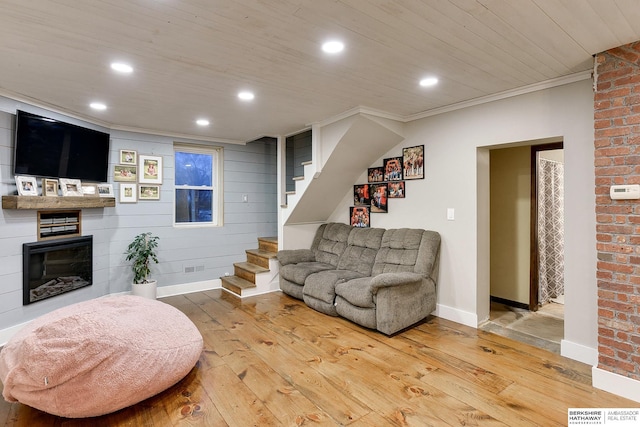 living room featuring hardwood / wood-style flooring, recessed lighting, ornamental molding, stairway, and a glass covered fireplace