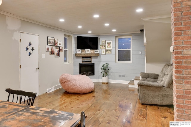 living area featuring recessed lighting, a fireplace, wood-type flooring, and crown molding