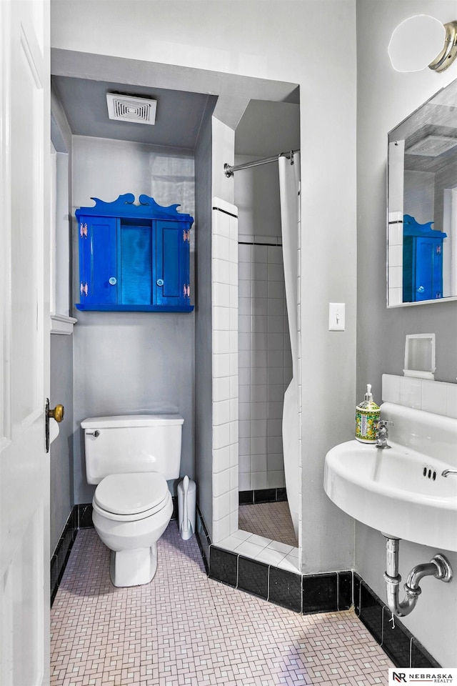 full bathroom featuring tiled shower, visible vents, toilet, and tile patterned floors