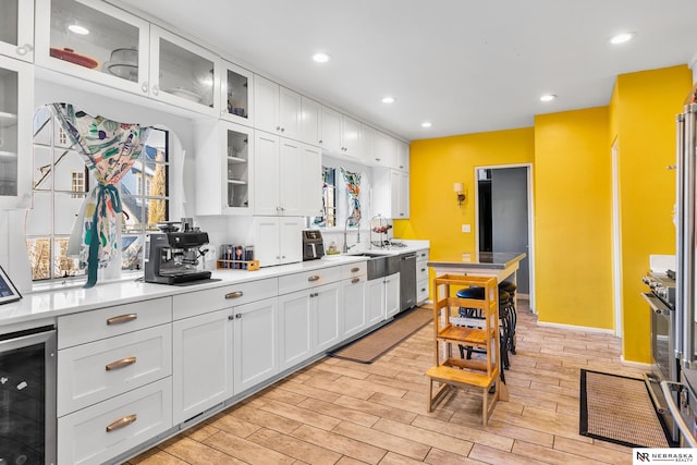 kitchen featuring light wood finished floors, wine cooler, white cabinetry, and light countertops