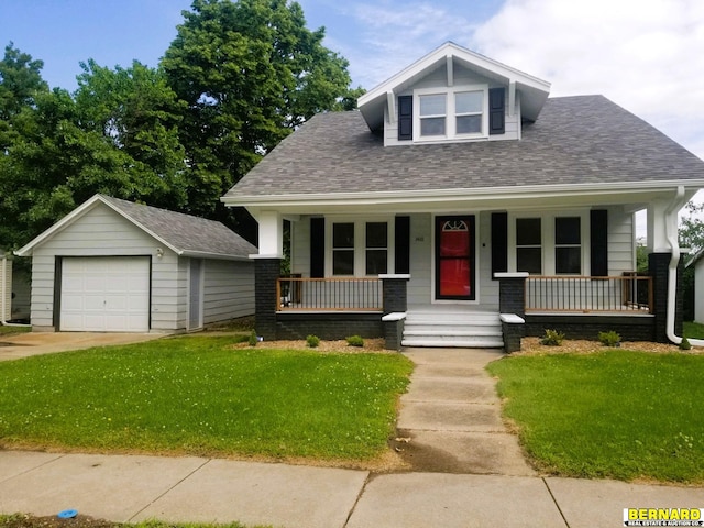 bungalow-style home featuring a detached garage, roof with shingles, an outbuilding, covered porch, and a front yard