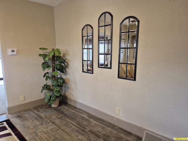 interior details with a textured wall, wood finished floors, and baseboards