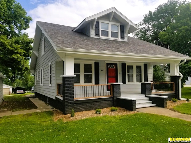 bungalow-style home featuring covered porch, a front lawn, and a shingled roof