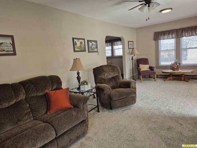 carpeted living area with ceiling fan and arched walkways