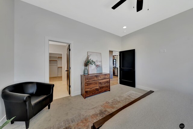 bedroom with light carpet, ceiling fan, a spacious closet, and baseboards