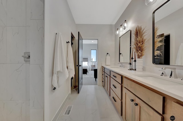 ensuite bathroom with marble finish floor, double vanity, a sink, and visible vents