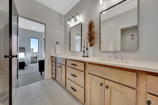 ensuite bathroom with marble finish floor, double vanity, a sink, and connected bathroom