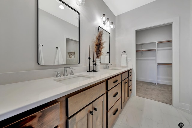 full bath with a walk in closet, marble finish floor, a sink, and double vanity