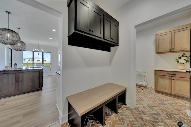 mudroom featuring a chandelier, brick floor, recessed lighting, a sink, and baseboards