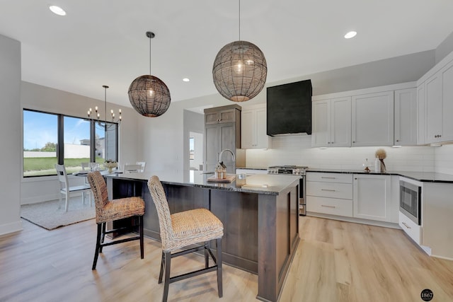 kitchen featuring appliances with stainless steel finishes, tasteful backsplash, a sink, and exhaust hood