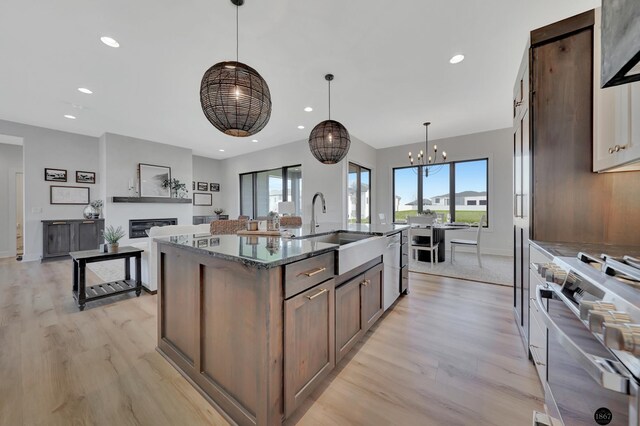 kitchen featuring stainless steel appliances, a glass covered fireplace, light wood-style flooring, and recessed lighting