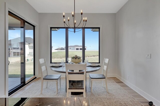 dining space with light wood-style floors, plenty of natural light, baseboards, and an inviting chandelier