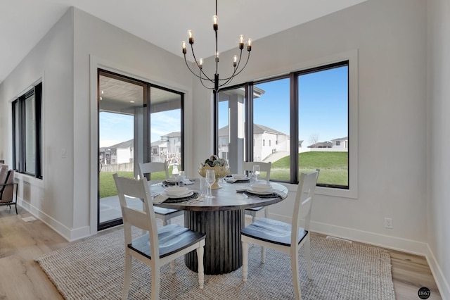 dining space featuring light wood-style floors, baseboards, and a notable chandelier