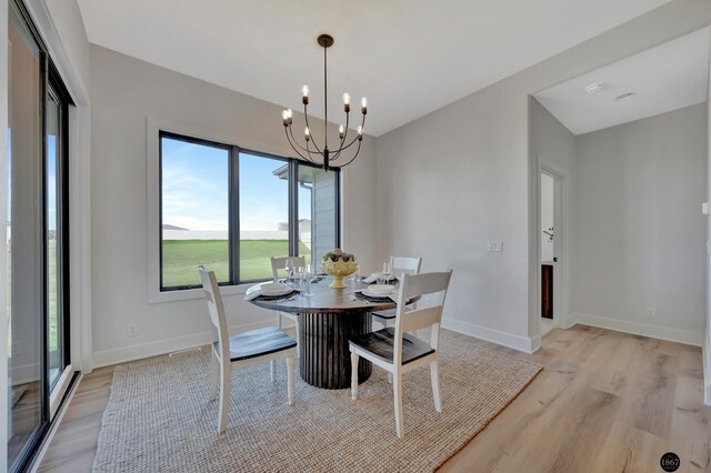 dining area featuring light wood-style flooring, baseboards, and a notable chandelier