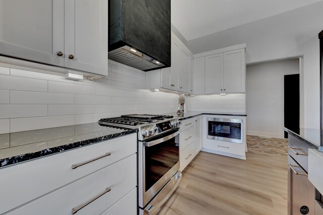 kitchen featuring light wood-style flooring, dark stone countertops, custom exhaust hood, built in microwave, and gas stove