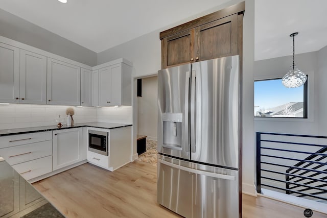 kitchen featuring white cabinets, built in microwave, light wood-type flooring, stainless steel refrigerator with ice dispenser, and backsplash