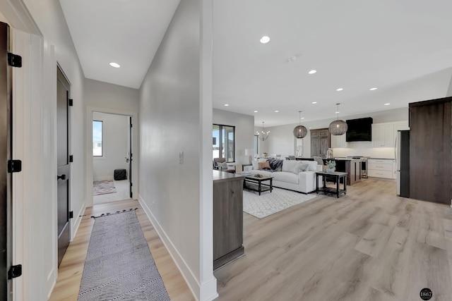 hall featuring recessed lighting, light wood finished floors, plenty of natural light, and an inviting chandelier