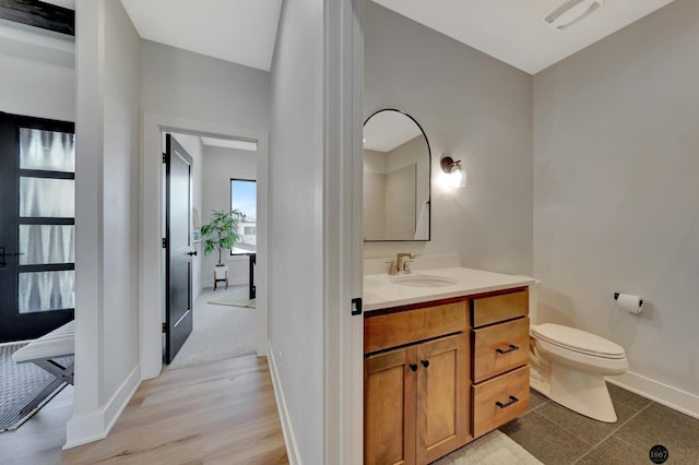 bathroom with visible vents, baseboards, toilet, wood finished floors, and vanity