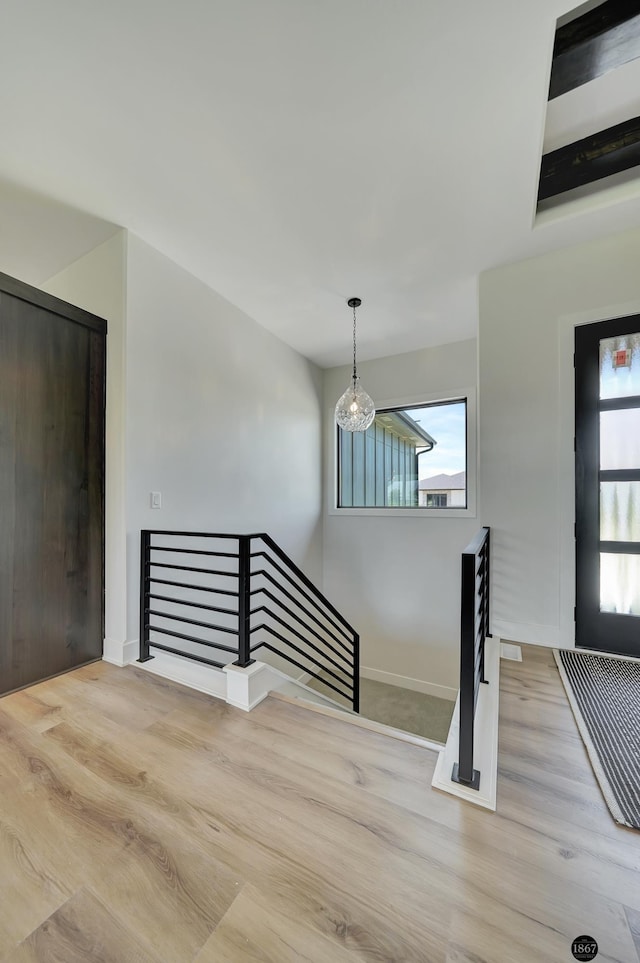 staircase featuring an inviting chandelier, baseboards, and wood finished floors