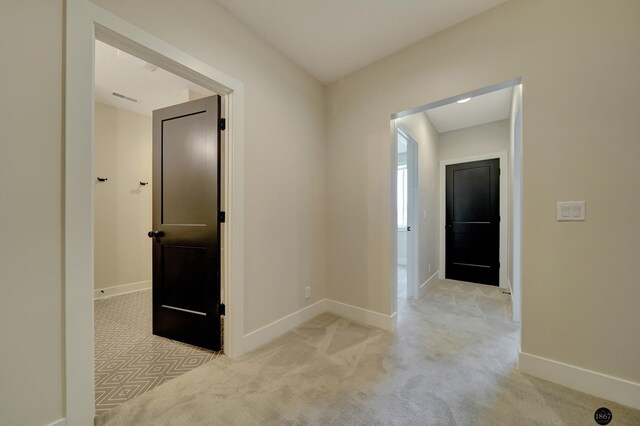 hall featuring visible vents, baseboards, and light colored carpet