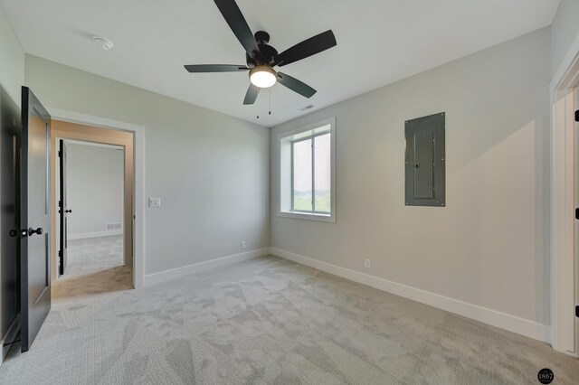 unfurnished bedroom with baseboards, electric panel, and light colored carpet