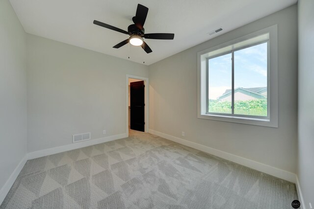 empty room featuring light carpet, visible vents, and baseboards