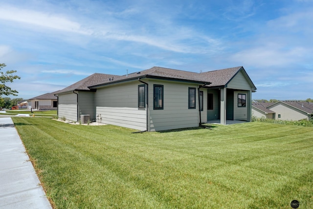 view of front of property featuring a front lawn, a shingled roof, and central air condition unit