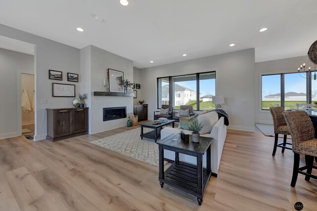 living area with a wealth of natural light, a glass covered fireplace, and light wood-type flooring