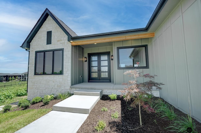 entrance to property with stone siding, french doors, and a porch