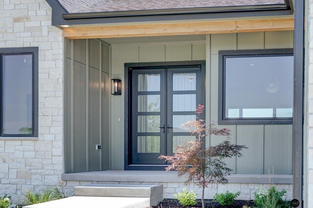 doorway to property featuring stone siding and a shingled roof