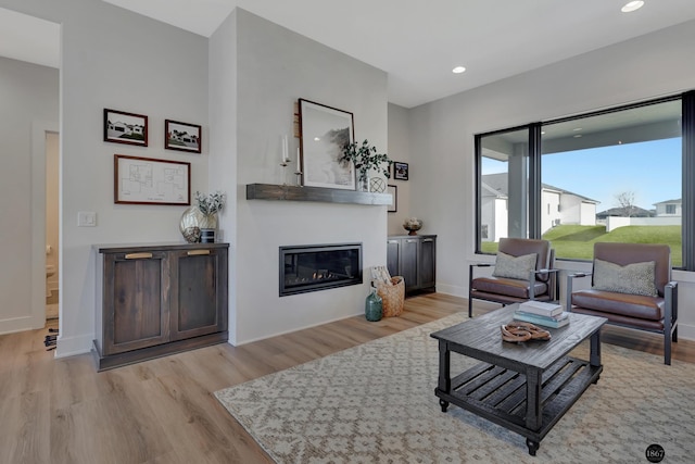 living room with a glass covered fireplace, recessed lighting, baseboards, and wood finished floors