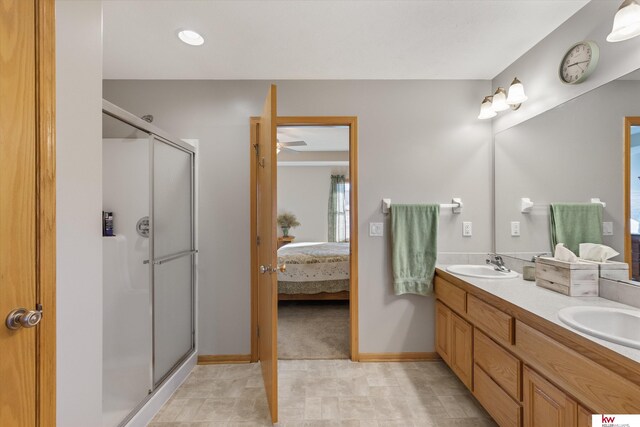 ensuite bathroom with a shower stall, double vanity, a sink, and connected bathroom