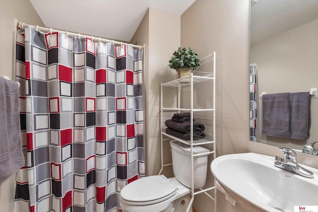 bathroom featuring curtained shower, a sink, and toilet