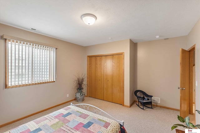 carpeted bedroom with baseboards, visible vents, and a closet