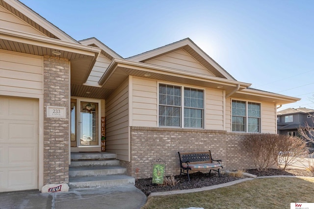 view of exterior entry featuring brick siding and an attached garage