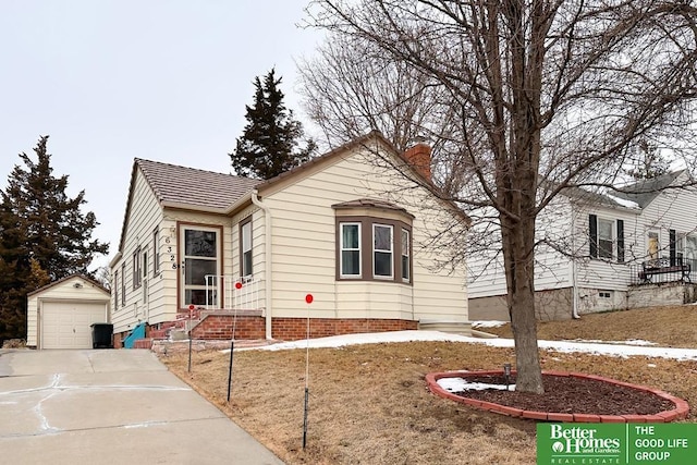 view of front of house featuring a garage, concrete driveway, a chimney, and an outdoor structure