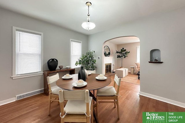 dining room with a brick fireplace, visible vents, a wealth of natural light, and wood finished floors