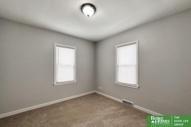 empty room with carpet, visible vents, and baseboards