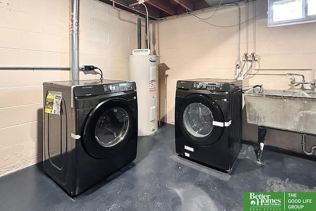 washroom featuring concrete block wall, laundry area, independent washer and dryer, electric water heater, and a sink