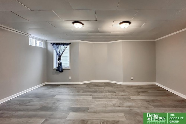 basement featuring crown molding, baseboards, and wood finished floors