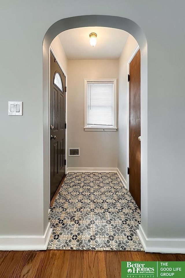 foyer entrance featuring arched walkways, visible vents, and baseboards