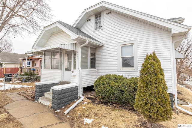 bungalow featuring fence and roof with shingles