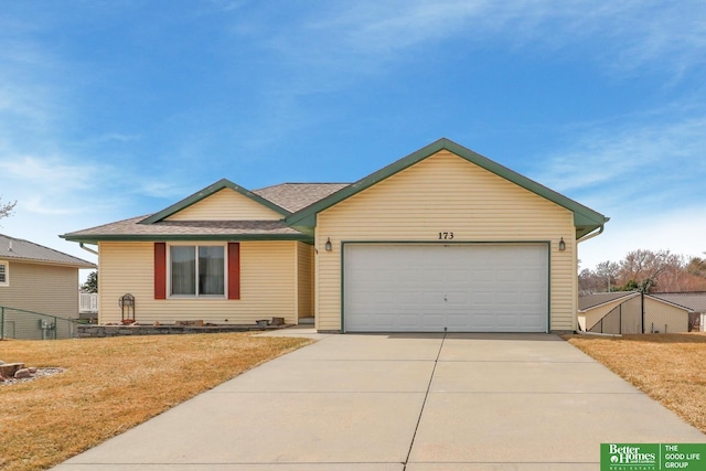 ranch-style house with a shingled roof, concrete driveway, a garage, and a front yard