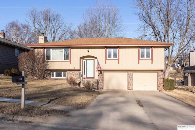 bi-level home with a garage, concrete driveway, brick siding, and a chimney