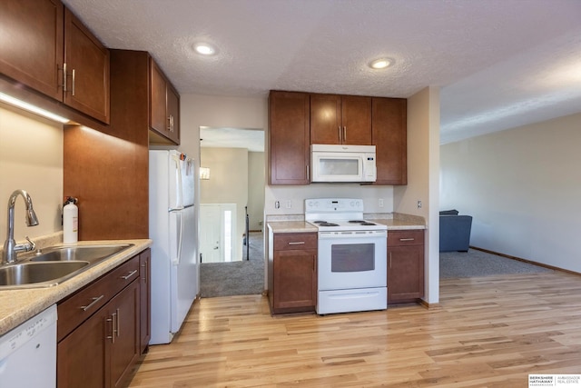 kitchen with light countertops, white appliances, light wood-type flooring, and a sink