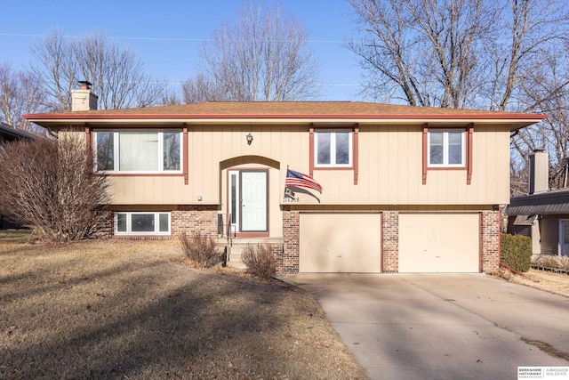 bi-level home featuring brick siding, driveway, a chimney, and an attached garage