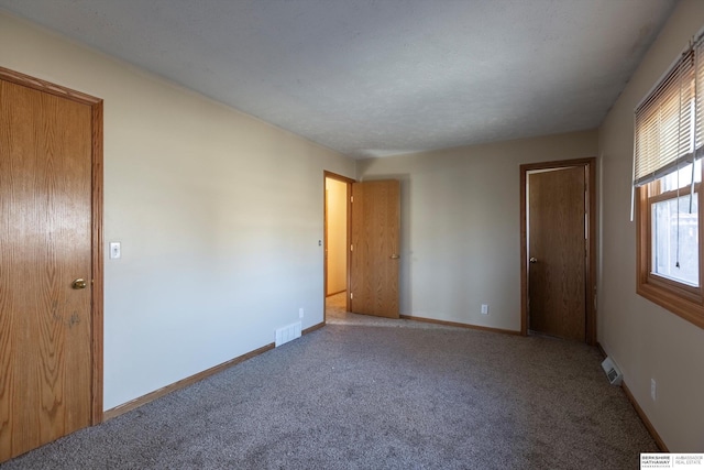 carpeted spare room with visible vents and baseboards