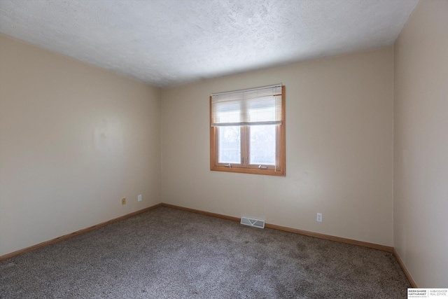 carpeted spare room with baseboards, visible vents, and a textured ceiling