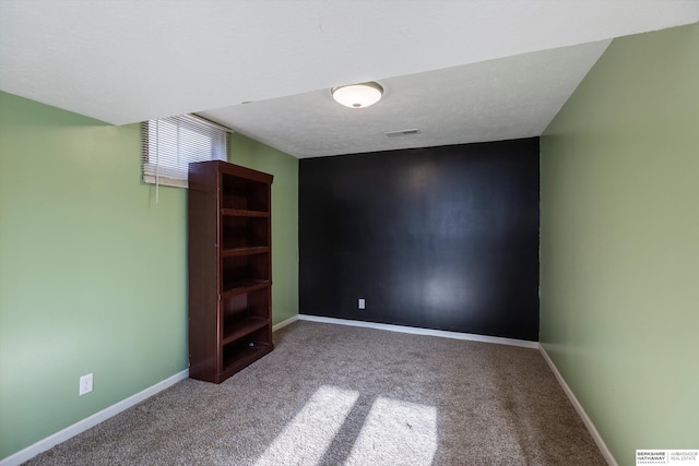 interior space with a textured ceiling, carpet flooring, visible vents, and baseboards