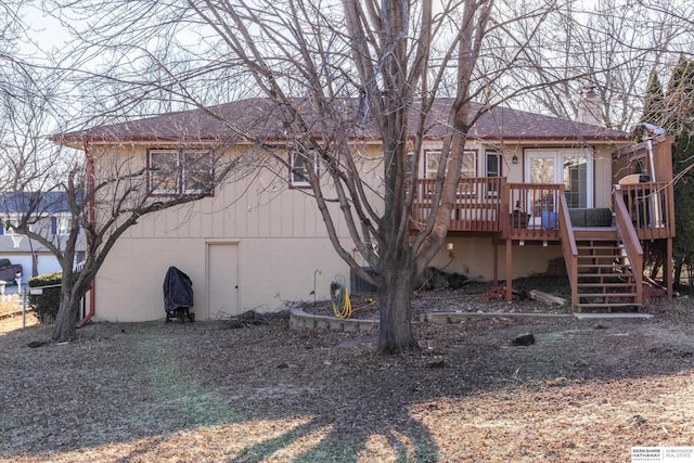 rear view of property featuring a shingled roof, stairway, a chimney, and a wooden deck